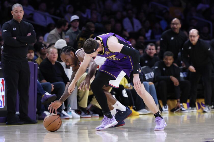 Los Angeles, CA - February 28: Los Angeles Clippers forward Kawhi Leonard, left, and Los Angeles Lakers guard Austin Reaves go after a loose ball during the first half action. Lakers vs Clippers at Crypto.com Arena in Los Angeles Friday, Feb. 28, 2025. (Allen J. Schaben / Los Angeles Times)