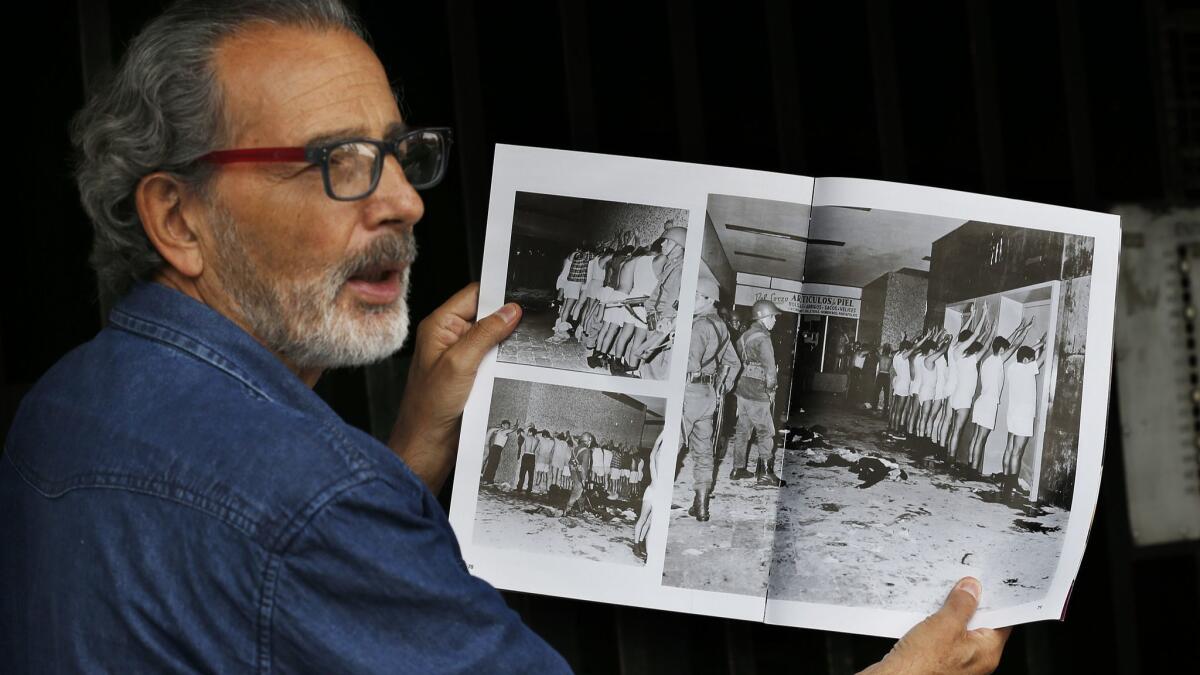 Enrique Espinosa shows a magazine photo in which he and other demonstrators are being detained by armed soldiers during the Tlatelolco massacre in Mexico City.