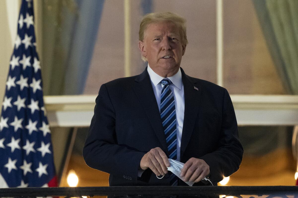 Trump removes his mask while looking out from White House balcony