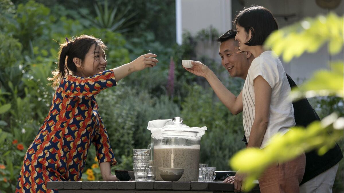 Yong Ha Jeong, left, a Los Angeles-based sool brewer, cheers with friends with a cap of makgeolli.