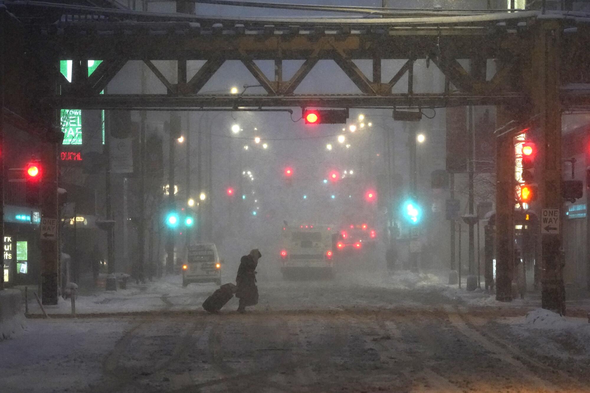 A lone pedestrian navigates a Chicago street in windy, falling snow