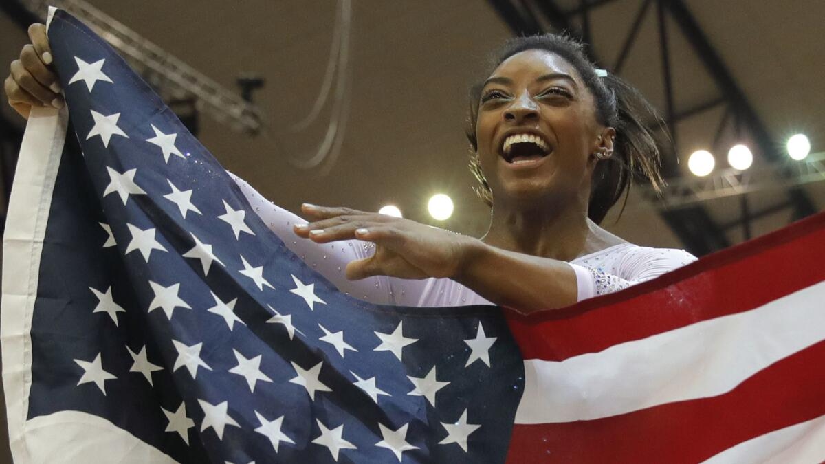 Simone Biles celebrates with the U.S. flag after winning her fourth world all-around championship.