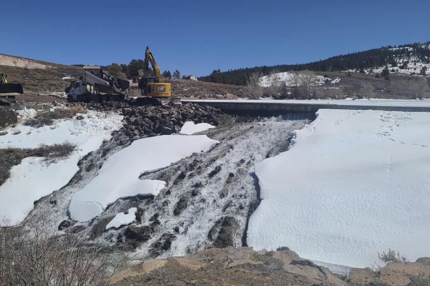 In this photo provided by the Utah Division of Water Rights, crews use heavy machinery to place boulders downstream of the cracked Panguitch Lake Dam to reinforce the wall, Wednesday, April 10, 2024, in Panguitch, Utah. (Matt Call/Utah Division of Water Rights via AP)
