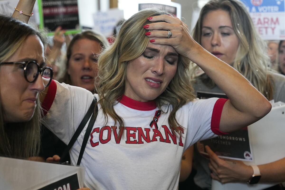 A woman wearing a "Covenant" shirt is overcome with emotion outside the House chamber in Tennessee. 