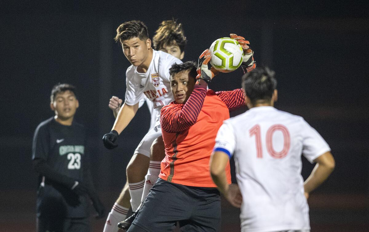 Costa Mesa goalkeeper Walter Olmedo grabs the ball out of the air as Estancia's Richard Cervantes goes up to get it during an Orange Coast League match on Wednesday.