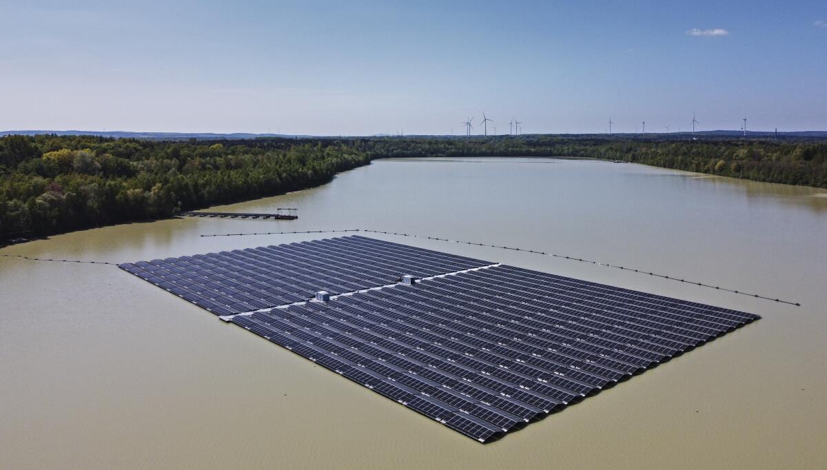File - Solar panels on Germany's biggest floating photovoltaic plant produce energy under a blue sky on a lake in Haltern, Germany, Tuesday, May 3, 2022. Long periods of sunshine took solar power generation in Europe to a record high this summer, helping reduce the need for gas imports, according to a report Thursday. Energy think tank Ember said the European Union generated 12% of its electricity from solar power from May to August, up from 9% during the same period last year. (AP Photo/Martin Meissner, File )