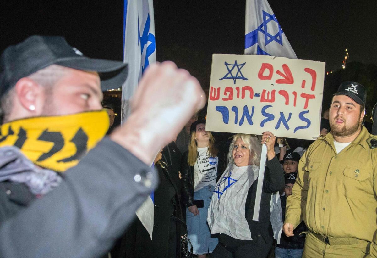 An Israeli citizen holds a banner reading in Hebrew: "Fighters, the people are with you" during a demonstration in Tel Aviv on Thursday to support an Israeli soldier who was suspended after being caught on video shooting a wounded Palestinian assailant in the head as he lay on the ground.