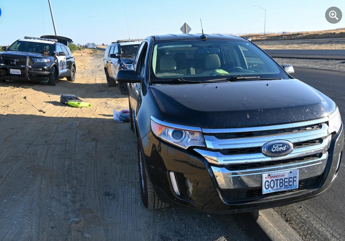 A pickup truck with the license plate GOTBEEF and two CHP vehicles sit along the shoulder of a freeway.