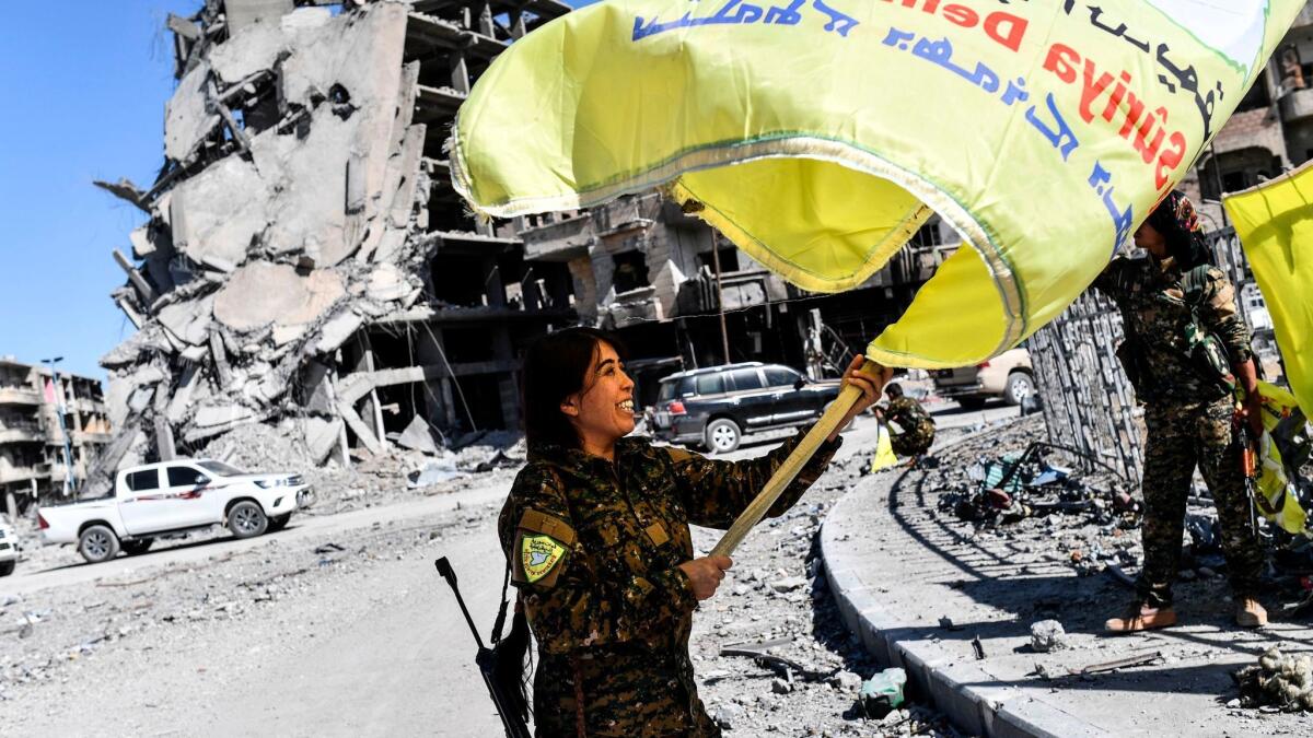 Rojda Felat, a Syrian Democratic Forces commander, waves her group's flag at the iconic Al-Naim square in Raqqah, Syria, on Oct. 17, 2017.