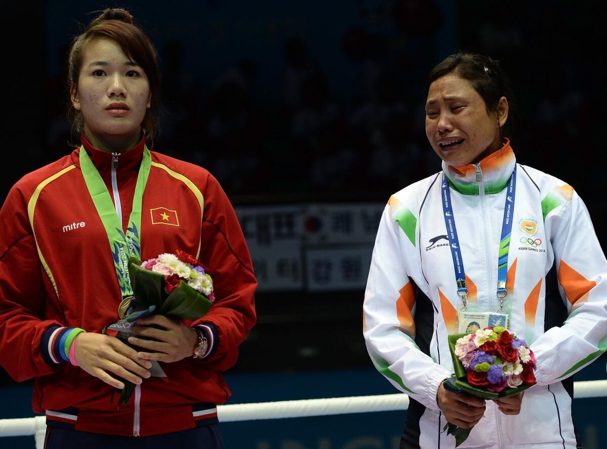 India's Laishram Sarita Devi, right, standing next to fellow bronze medalist Luu Thi Duyen of Vietnam, refused to wear her medal Wednesday during the women's lightweight boxing medal ceremony at the 2014 Asian Games in Incheon, South Korea.