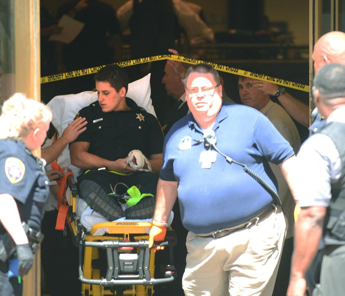 A sheriff's deputy with a hand injury is taken from the lobby of the Chester County Courthouse following a shooting in Pennsylvania.