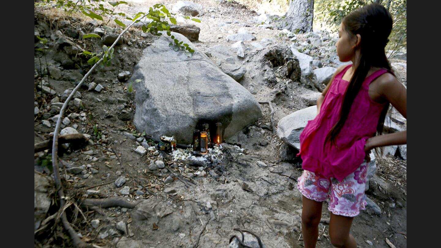 Nine-year old Talulah Shadrick of Altadena pauses to look at what seems to be an altar with offerings and lit candles about two miles into the Gabrielino Trail, next to the Arroyo Seco in the Angeles National Forest north of Altadena, on Tuesday, Aug. 8, 2017.