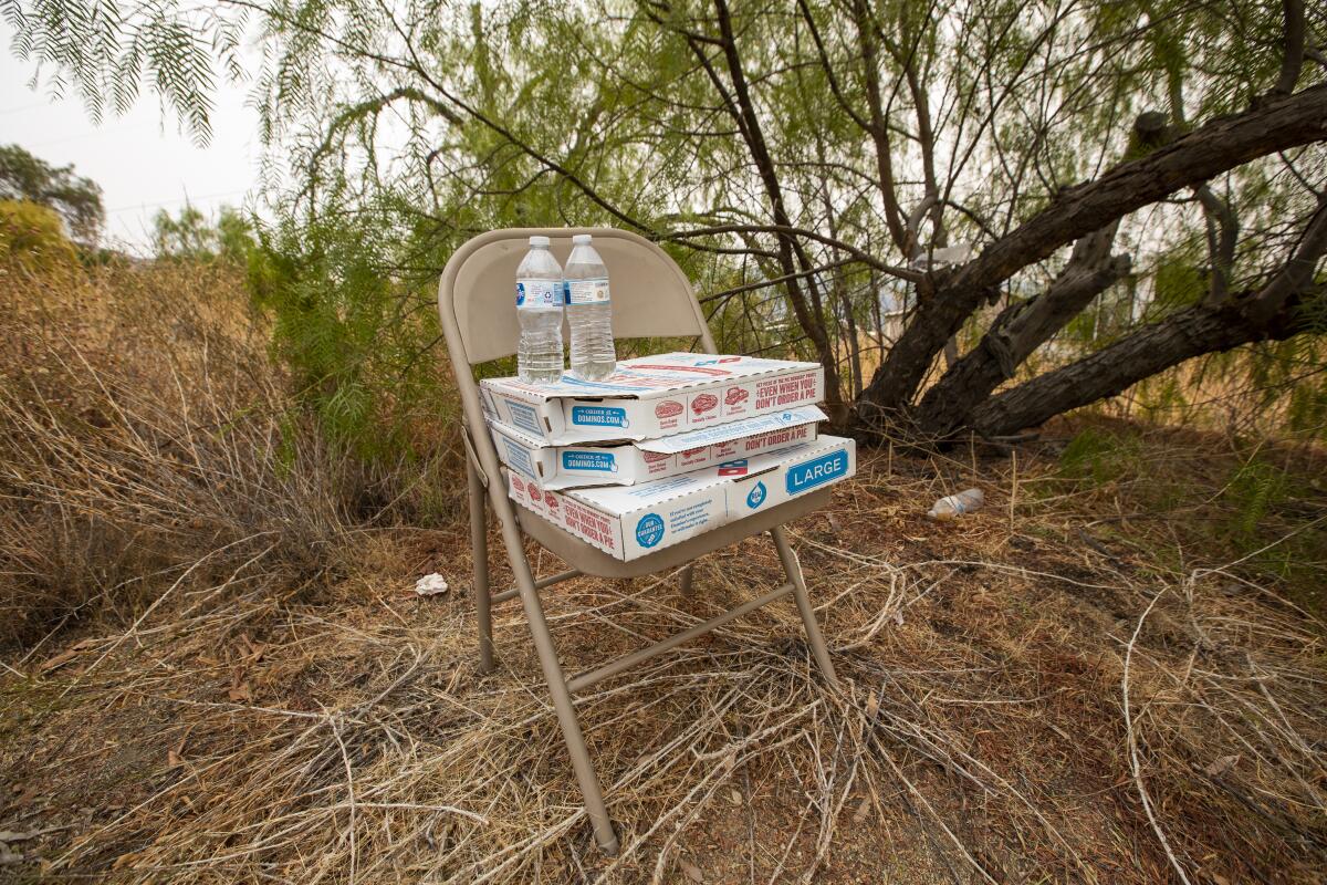A metal chair with boxes of pizza and water bottles.