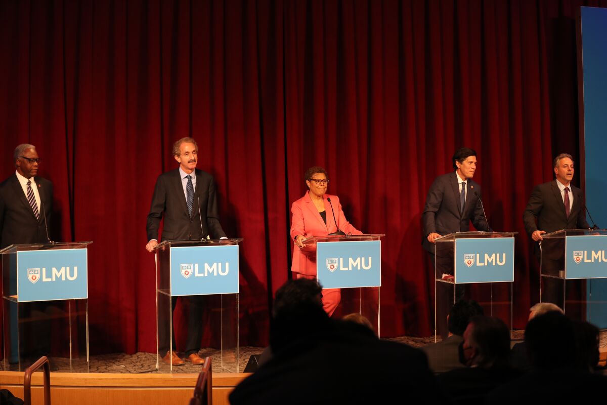 Five people stand in a row behind podiums on a stage.