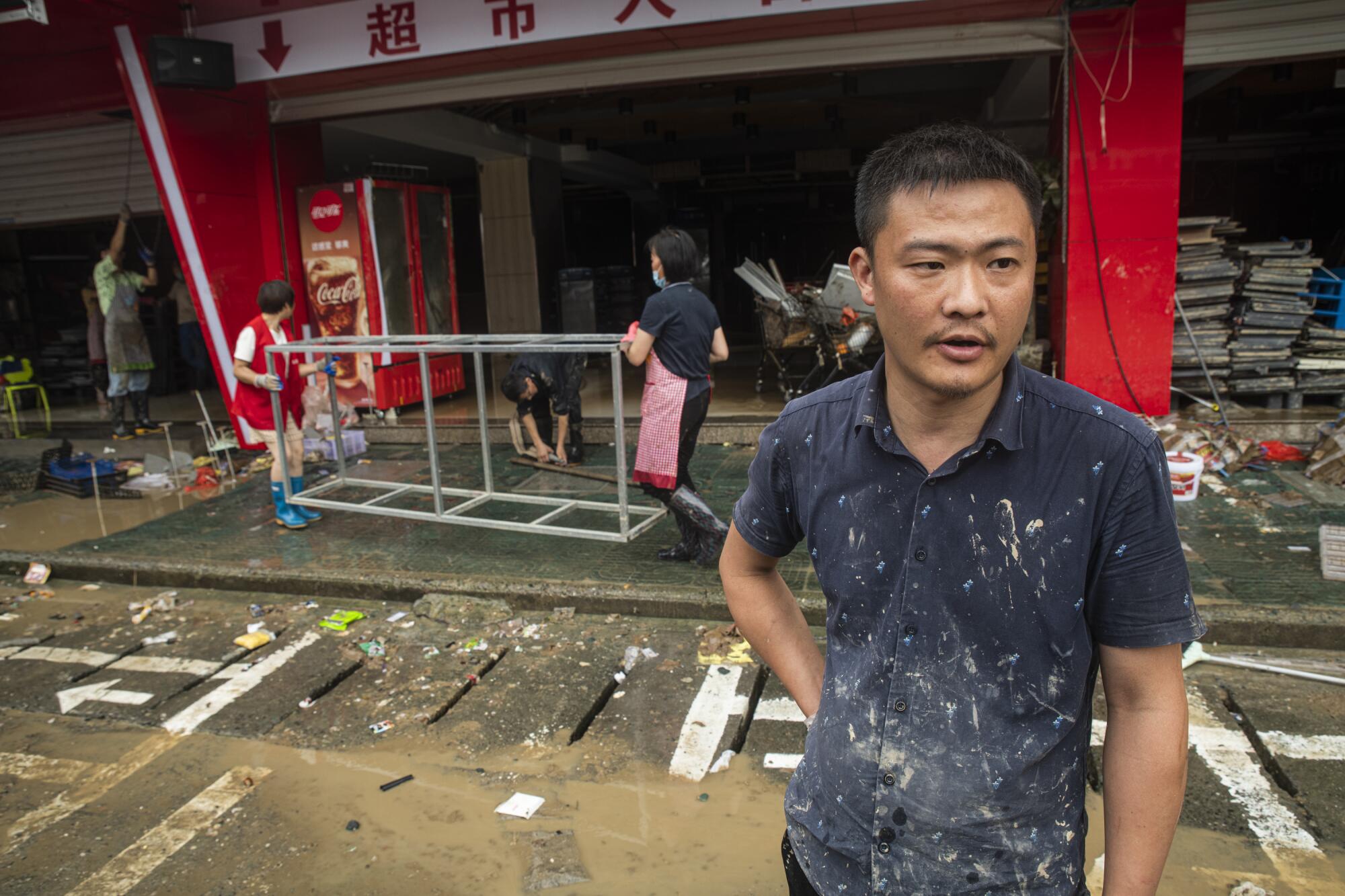 Yin Jianfeng stands outside the flooded supermarket he manages in Shexian, Anhui province.