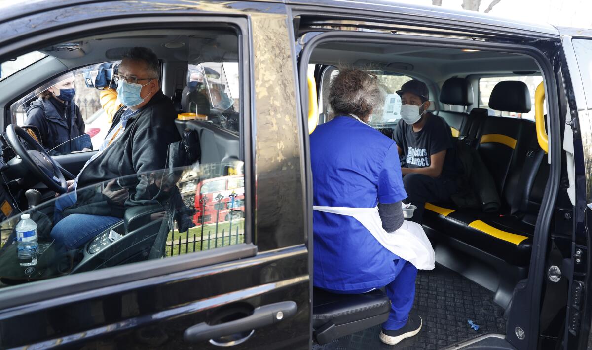 Dr Tamara Joffe prepares to administer a Covid-19 jab using the AstraZeneca vaccine to Leslie Reid in the back of a London Taxi cab during the pilot project of pop up vaccination drive 'Vaxi Taxi' in Kilburn, London, Sunday, Feb. 28, 2021. The pilot scheme, funded by the Covid Crisis Rescue Foundation, aims to help ferry supplies and patients to temporary clinics set up in faith and community centres across the capital. People don’t even need to leave the backseat if they didn’t want to in order to receive their inoculation. (AP Photo/Alastair Grant)