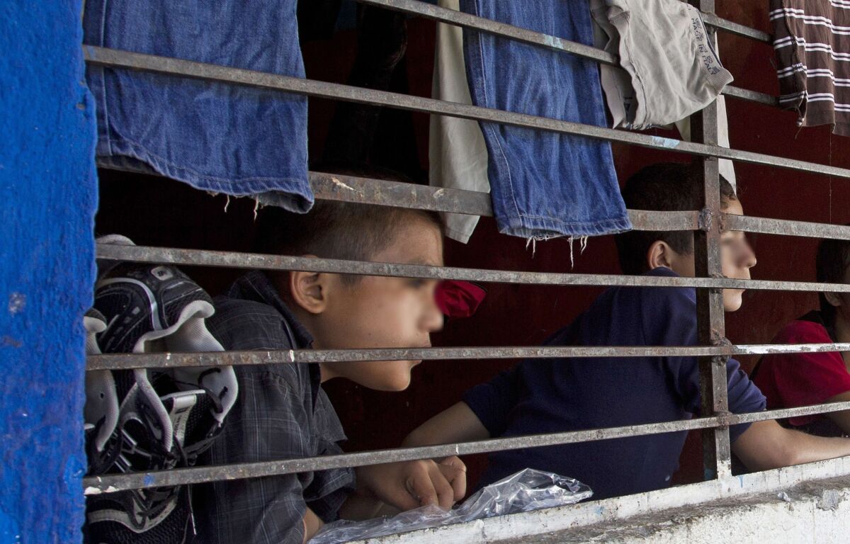 Children watch through a barred window inside "La Gran Familia" (The great family) shelter, where police earlier this week rescued almost 600 people, including 458 children in Zamora, Mexico.
