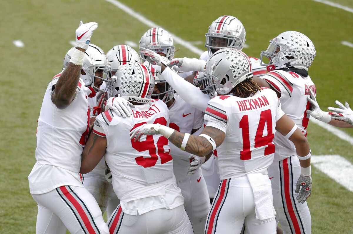 Ohio State players celebrate with Haskell Garrett (92) after his touchdown on an interception during the first half of an NCAA college football game against Michigan State, Saturday, Dec. 5, 2020, in East Lansing, Mich. (AP Photo/Al Goldis)