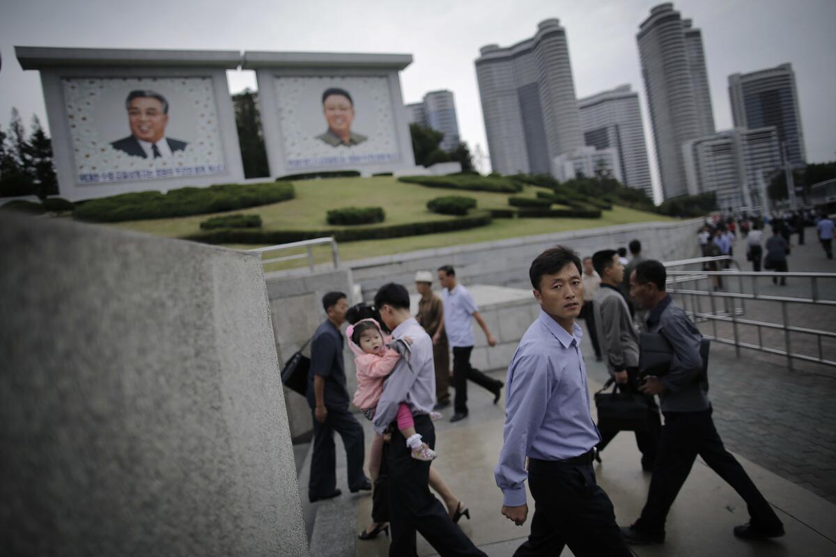 North Koreans walk in and out of a subway station during morning rush hour in Pyongyang, Sept. 28, 2016. In the background are portraits of the nation's late leaders Kim Il Sung, left, and his son Kim Jong-il.