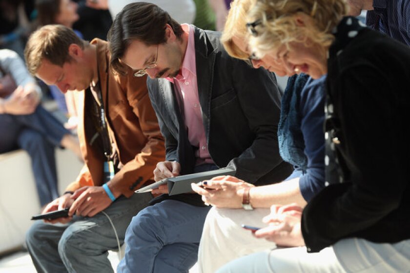 Attendees at a digital conference in Berlin, Germany, read and work on a variety of devices.
