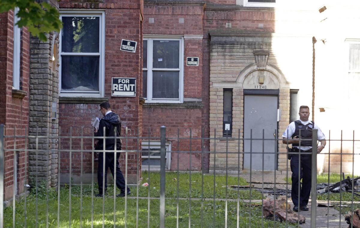 A Chicago police officer walks outside an apartment building as fire marshals sift through debris in the complex where four children died in an early morning fire Monday in Chicago.