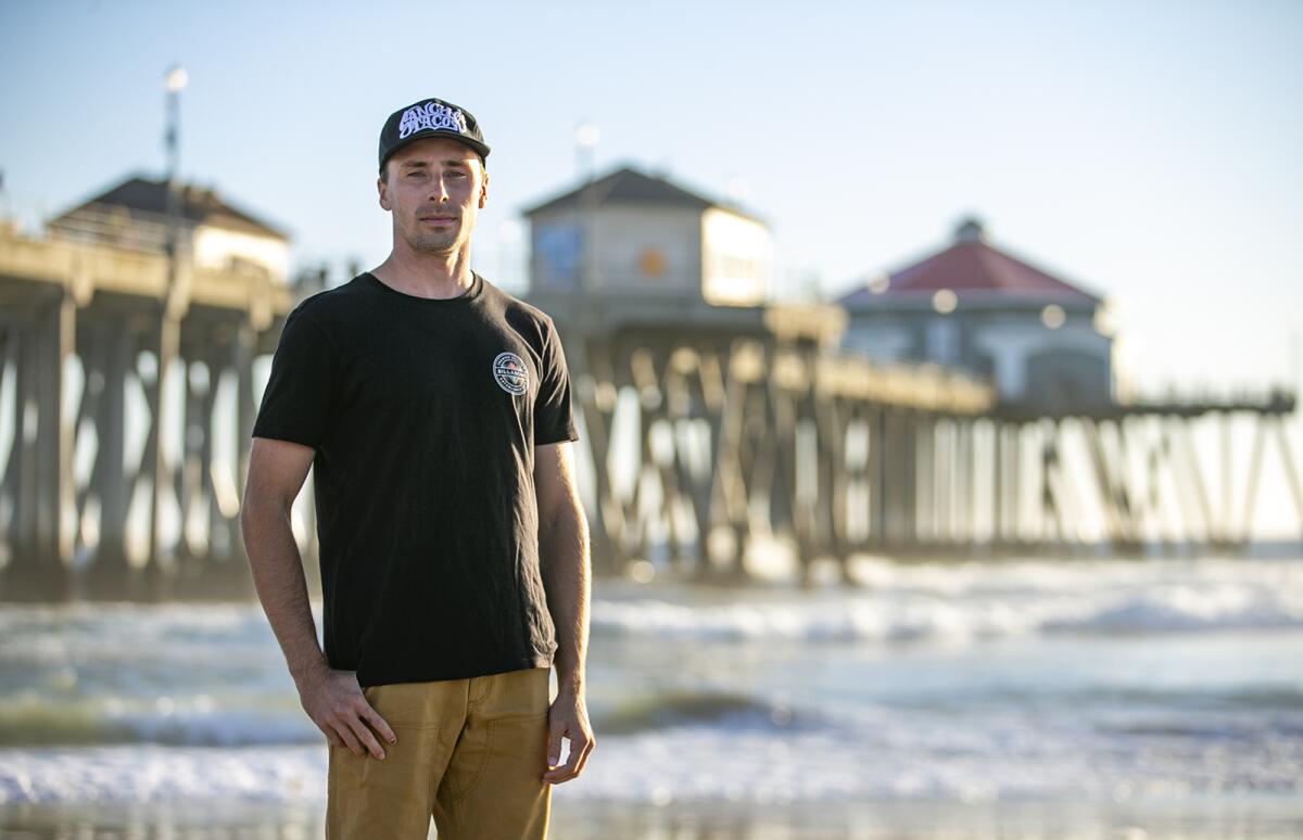 A man standing with the ocean and a pier in the background