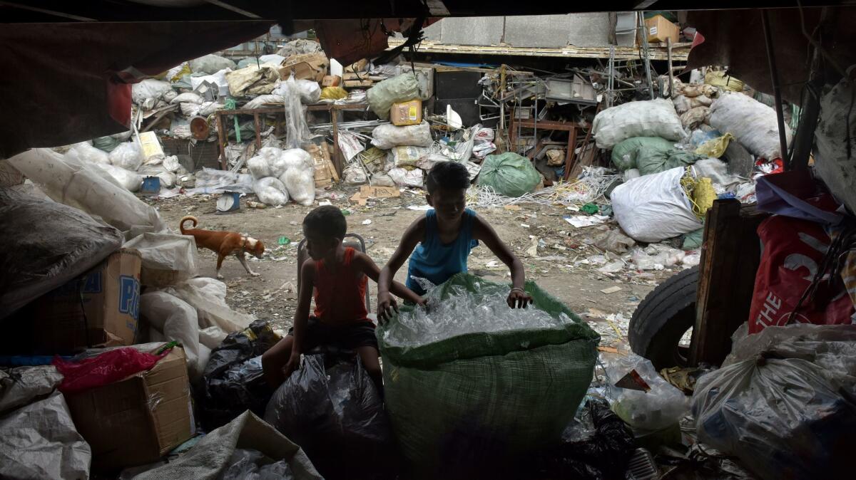 In this file photo, children sort waste products in an impoverished community in Manila.