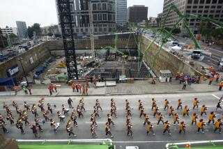 LOS ANGELES, CA-JANUARY 15, 2014: The USC marching band leads a parade on Figueroa St. in Downtown Los Angeles beside the Wilshire Grand Project, seen in background on February 15, 2014. The parade kicked what is being billed as the world's largest continuous concrete pour, expected to last nearly 20 hours. requiring 2100 truck loads delivering 21,200 cubic yards of concrete, weighing 82 million pounds. The 73 story, 1100 foot tall Wilshire Grand Center will be the tallest structure west of the Mississippi River, its developers say, when its 160 foot spire is included. (Photo by Mel Melcon/Los Angeles Times via Getty Images)