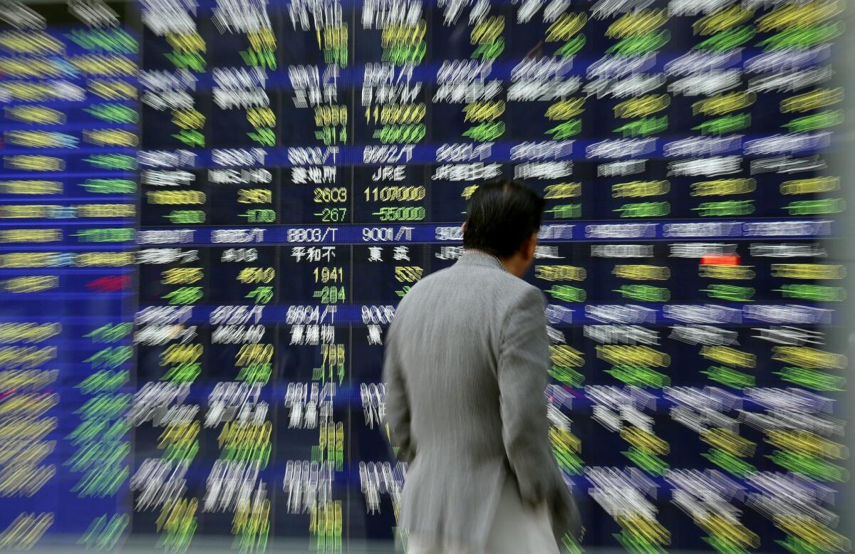 A Tokyo pedestrian eyes an electronic screen displaying stock quotes as the dramatic drop in Japan's Nikkei stock index unfolds on Thursday.
