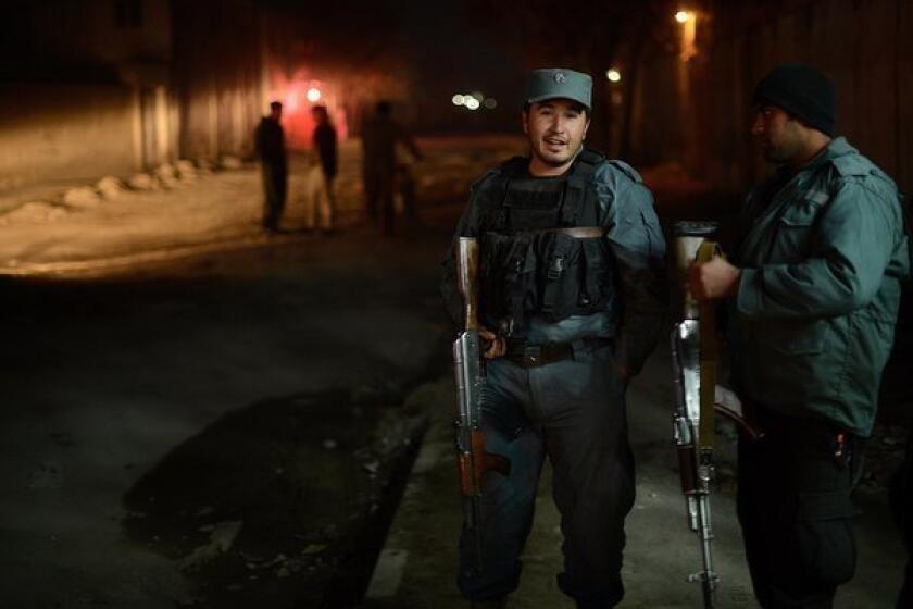 Afghan policemen block a road near the site of an attack at a spy agency guest house in Kabul, Afghanistan.