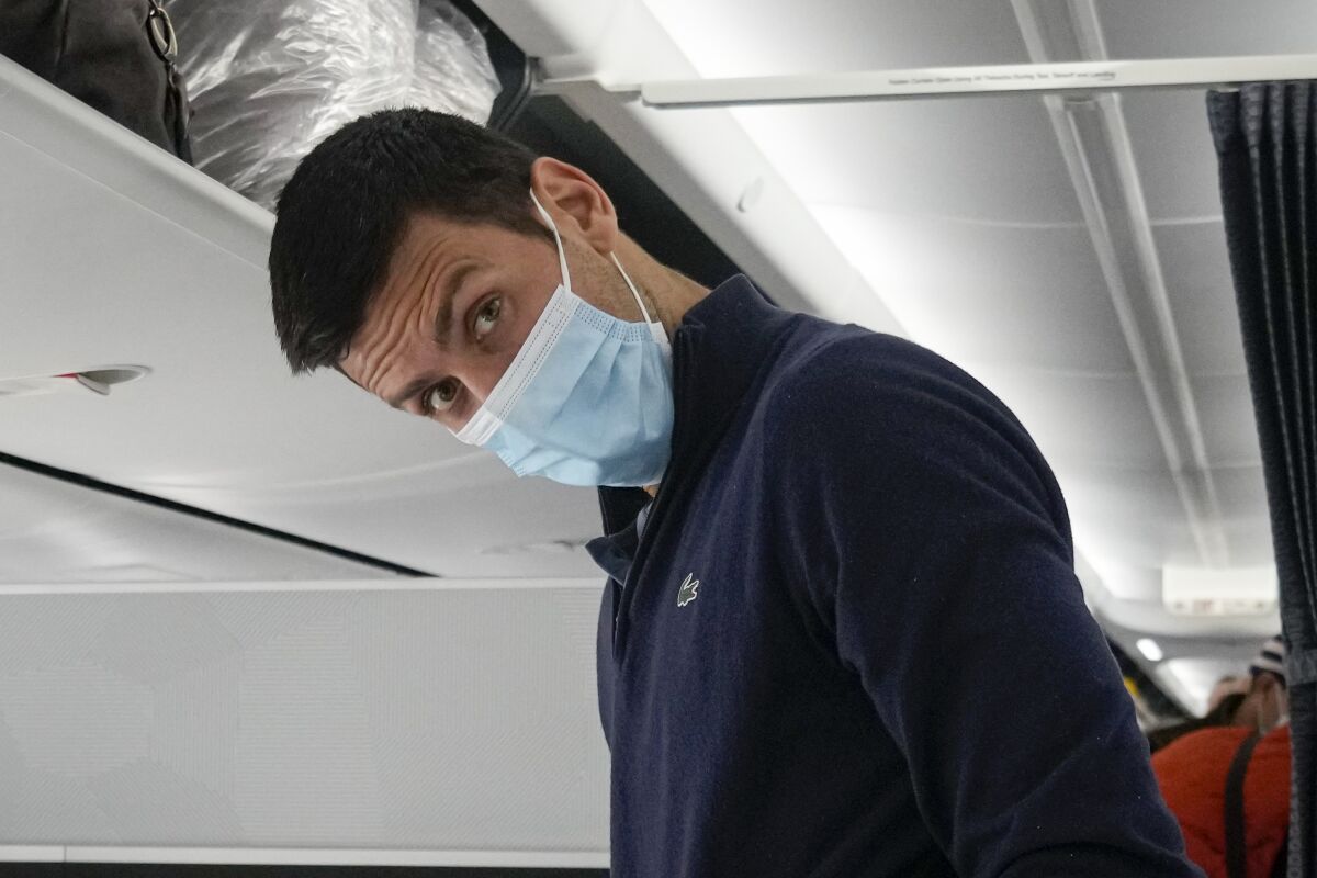 FILE - Recently deported from Australia for not being vaccinated against COVID-19, Novak Djokovic prepares to take his seat on a plane to Belgrade, in Dubai, United Arab Emirates, Monday, Jan. 17, 2022. Three Australian Federal Court judges on Thursday, Jan. 20, 2022, revealed their reasons for backing a government order to deport tennis star Novak Djokovic, explaining they did not consider the “merits or wisdom of the decision.” (AP Photo/Darko Bandic, File)