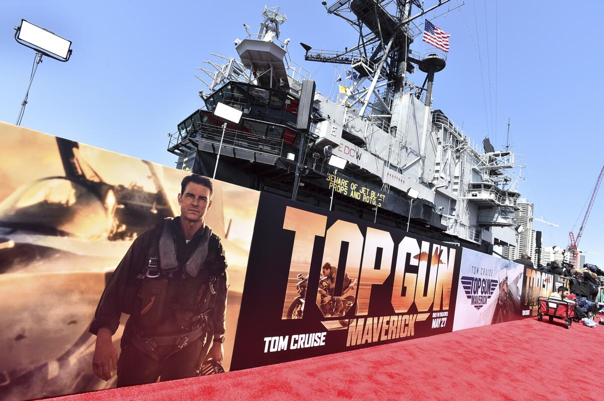 Red carpet and poster for "Top Gun: Maverick" in front of an aircraft carrier