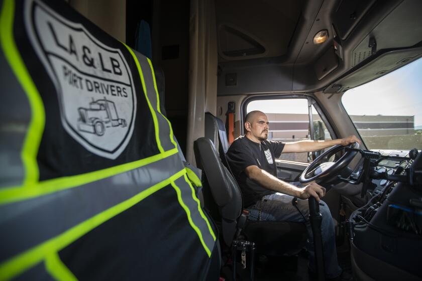 LONG BEACH, CALIF. -- SATURDAY, OCTOBER 26, 2019: Walter Diaz , 41, a Salvadoran immigrant, has been driving the ports of LA/LB for 20 years, stands with his truck, a 2012 Freightliner Cascadia in Long Beach, Calif., on Oct. 26, 2019. "As a truck driver, automation is going to be better for me," he says. "So i don't have to spend hours waiting for a load." As for the ILWU, "they don't care about the drivers. Never. If you say something they don't like, they'll kick you off....When I go to a terminal with robots, I spend just 45 minutes to pick up a load. So in one night, i can pick up four or five loads. So I'm making money." (Allen J. Schaben / Los Angeles Times)