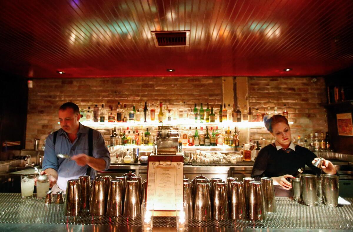Two bartenders at the Varnish in L.A. pouring drinks behind the bar.