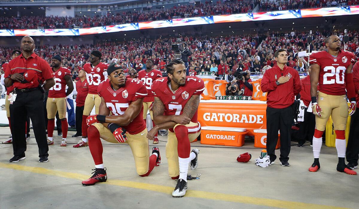 San Francisco 49ers quarterback Colin Kaepernick, center, and teammate Eric Reid take a knee during the national anthem before the team's Sept. 12, 2016, game against the Rams.