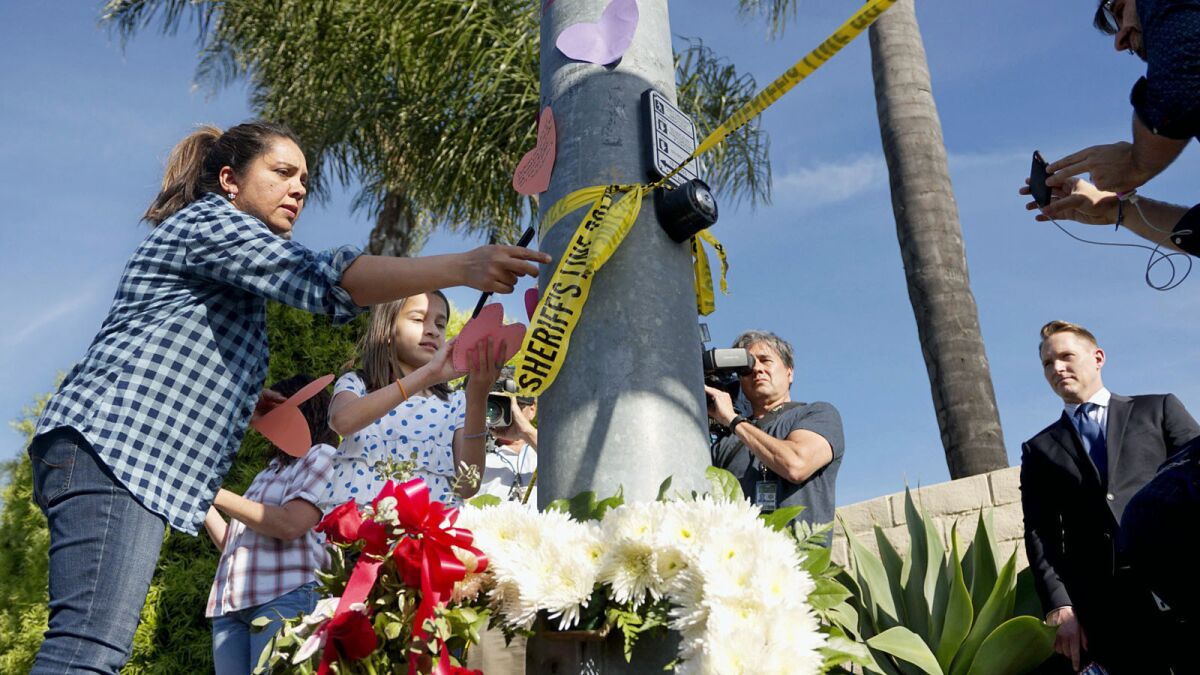 A woman and a young girl place notes on a pole across the street from the Chabad of Poway Synagogue after the shooting.