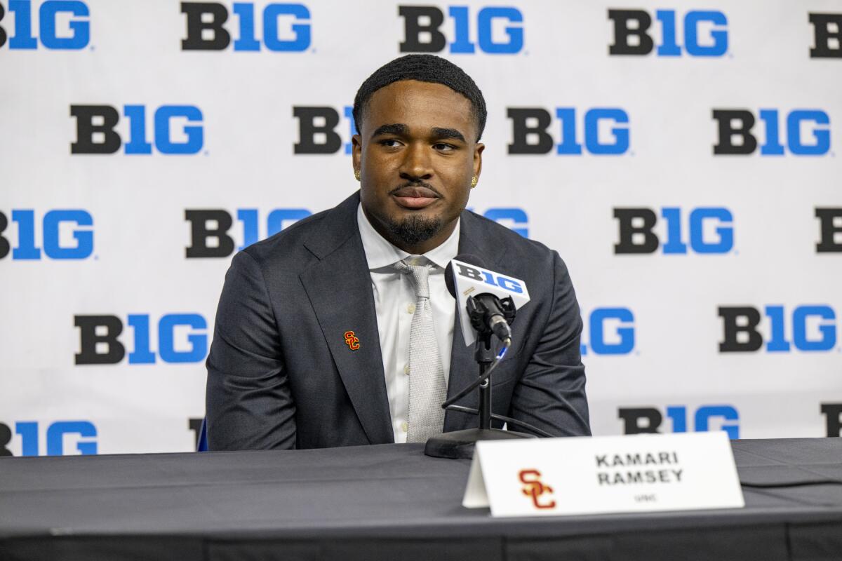 USC'den Kamari Ramsey takım elbiseyle mikrofonun arkasında oturuyor ve Big Ten medya günlerinde muhabirlerin sorularını yanıtlıyor