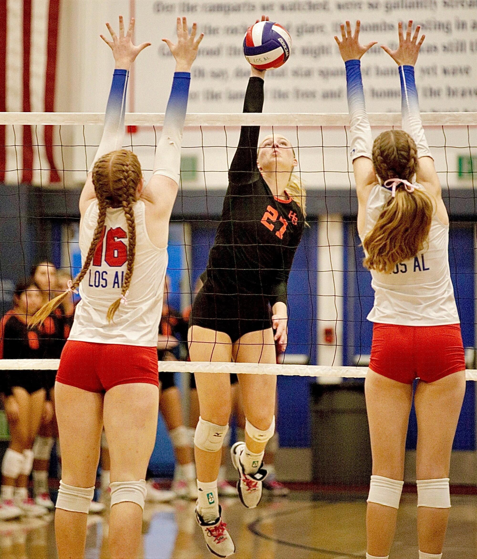 Huntington Beach junior opposite hitter Taylor Ponchak delivers a kill between two Los Alamitos blockers.