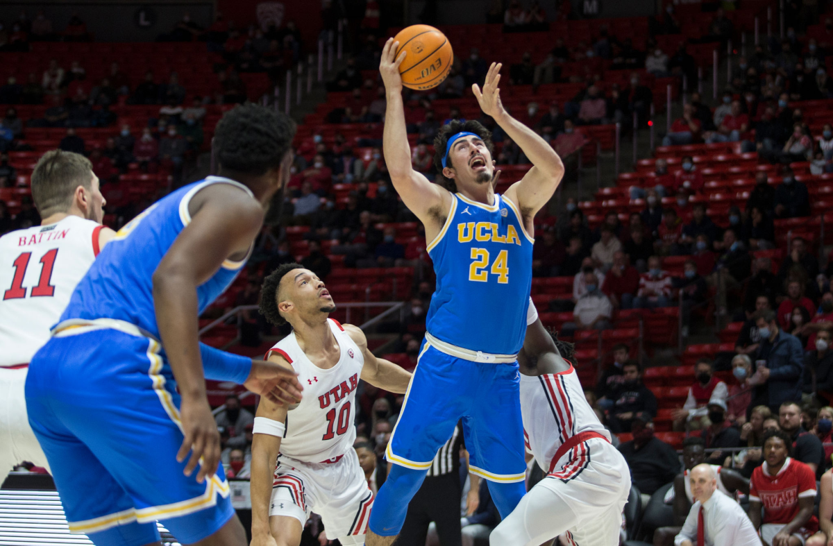 A UCLA basketball player jumps with the ball in his hands