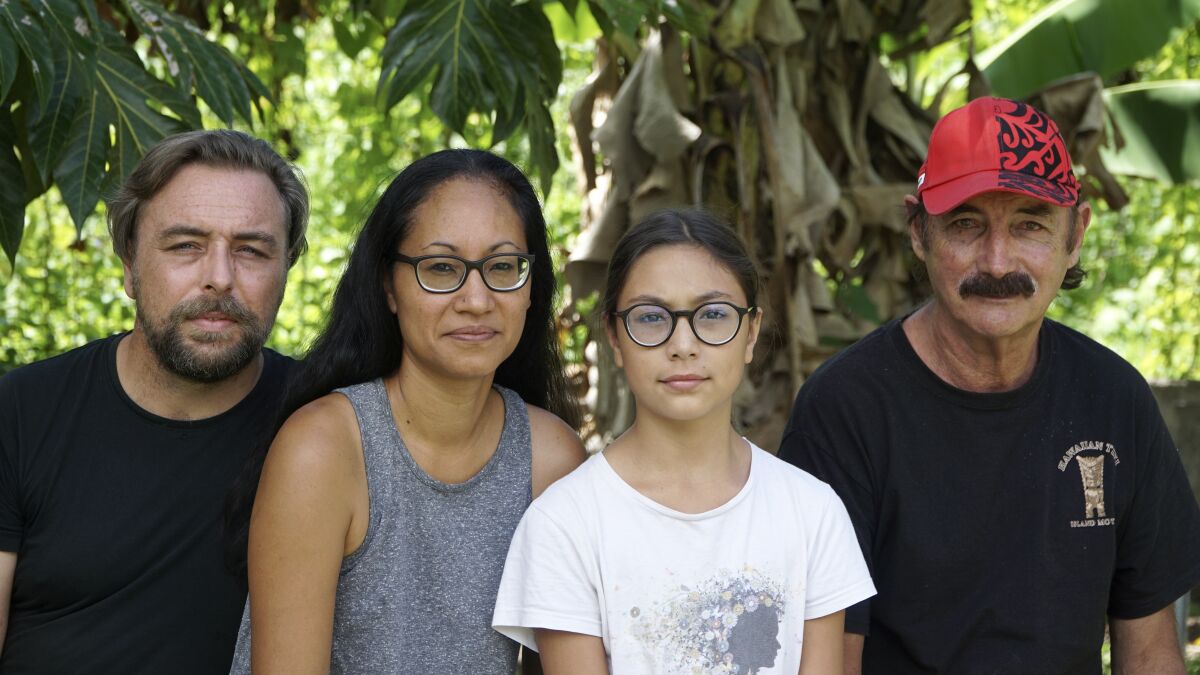 A group who have been stranded in Tahiti, pictured from left, Benjamin Baude, Kissy Ika Chavez Baude, Gaïa Baude Ika and Thierry Gourtay in Afareaitu on Moorea Island, Tahiti, Saturday, Sept. 19, 2020. A group of 25 residents from remote Easter Island has been stranded far from home for six months now. Many arrived in March planning to stay for just a few weeks. But they got stuck when the virus swept across the globe and their flights back home on LATAM airlines were canceled. LATAM says it doesn't know when it will restart the route.(Teraihau Rio via AP)