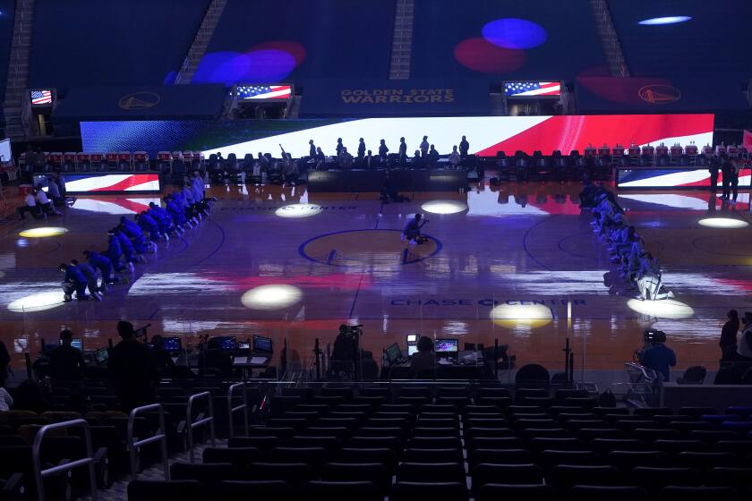 Players and coaches from the Golden State Warriors, left, and the Los Angeles Clippers kneel during the national anthem before an NBA basketball game in San Francisco, Wednesday, Jan. 6, 2021. (AP Photo/Jeff Chiu)