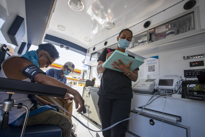 Nurse Jacqueline Ramirez takes blood pressure notes with patient Rene, left, and Dr. Coley King.