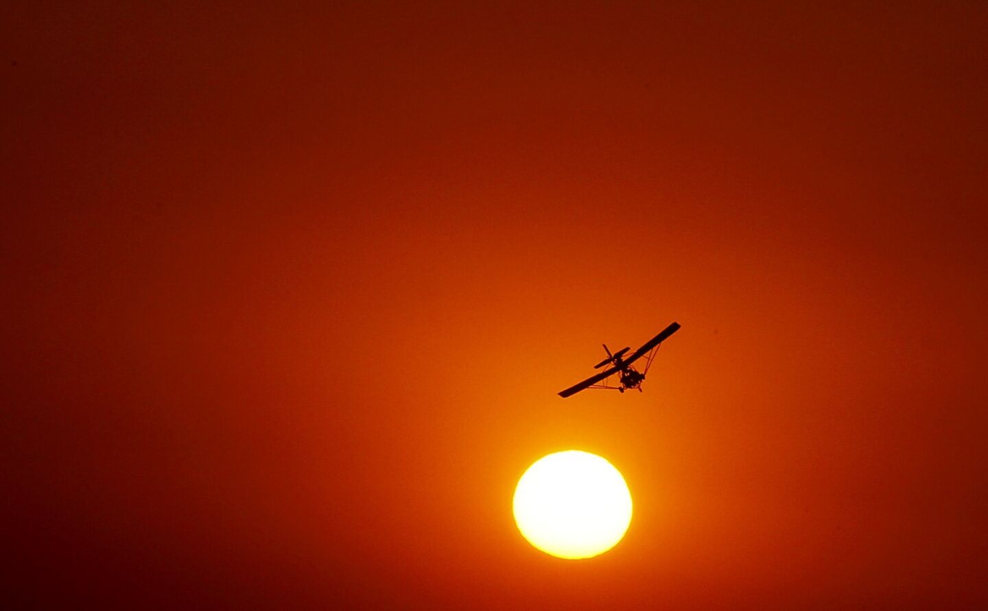 A light aircraft circles the Camarillo Airport against a sun and sky made red by smoke from the Springs fire, which showed signs of slowing Friday.