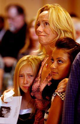 Susanne McGraham-Paisley hugs daughter Haley, left, and friend Eneida Diaz during services for the woman's brother, John Robert McGraham. More than 300 attended.