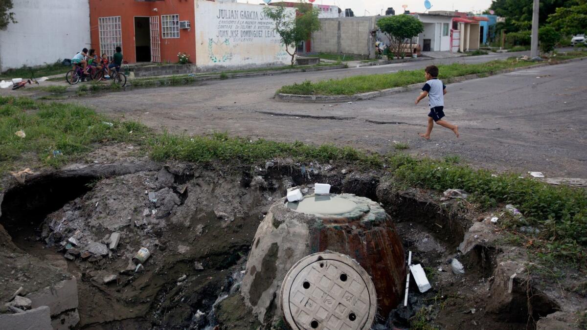 A child walks near a crater in Homex's Colinas de Santa Fe development in Veracruz, Mexico, in 2016. The SEC has filed civil charges against four former top Homex officials but has been unable to deliver a summons to them.