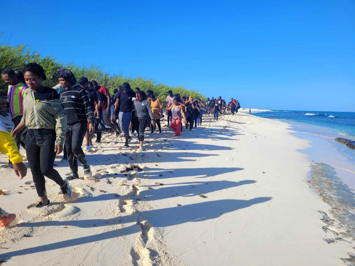 Migrantes rescatados caminan a la orilla de la playa, el jueves 28 de julio de 2022, en la Isla de Mona