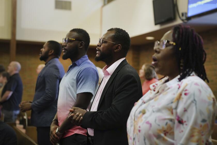 Members of the Haitian community in Springfield, Ohio, from left, Lindsay Aime, James Fleurijean, Viles Dorsainvil, and Rose-Thamar Joseph, stand for worship at Central Christian Church, on Sunday, Sept. 15, 2024. (AP Photo/Jessie Wardarski)