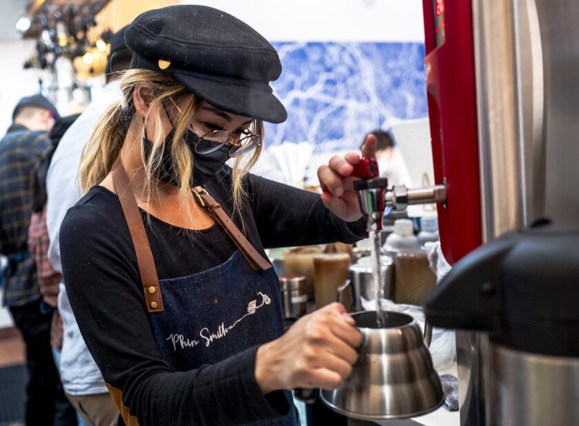 A barista makes coffee at a coffee shop.