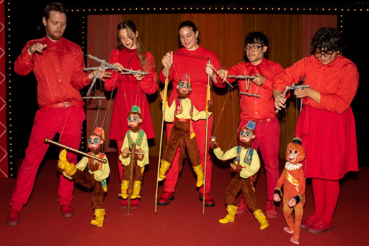 Five people dressed in red hold puppets