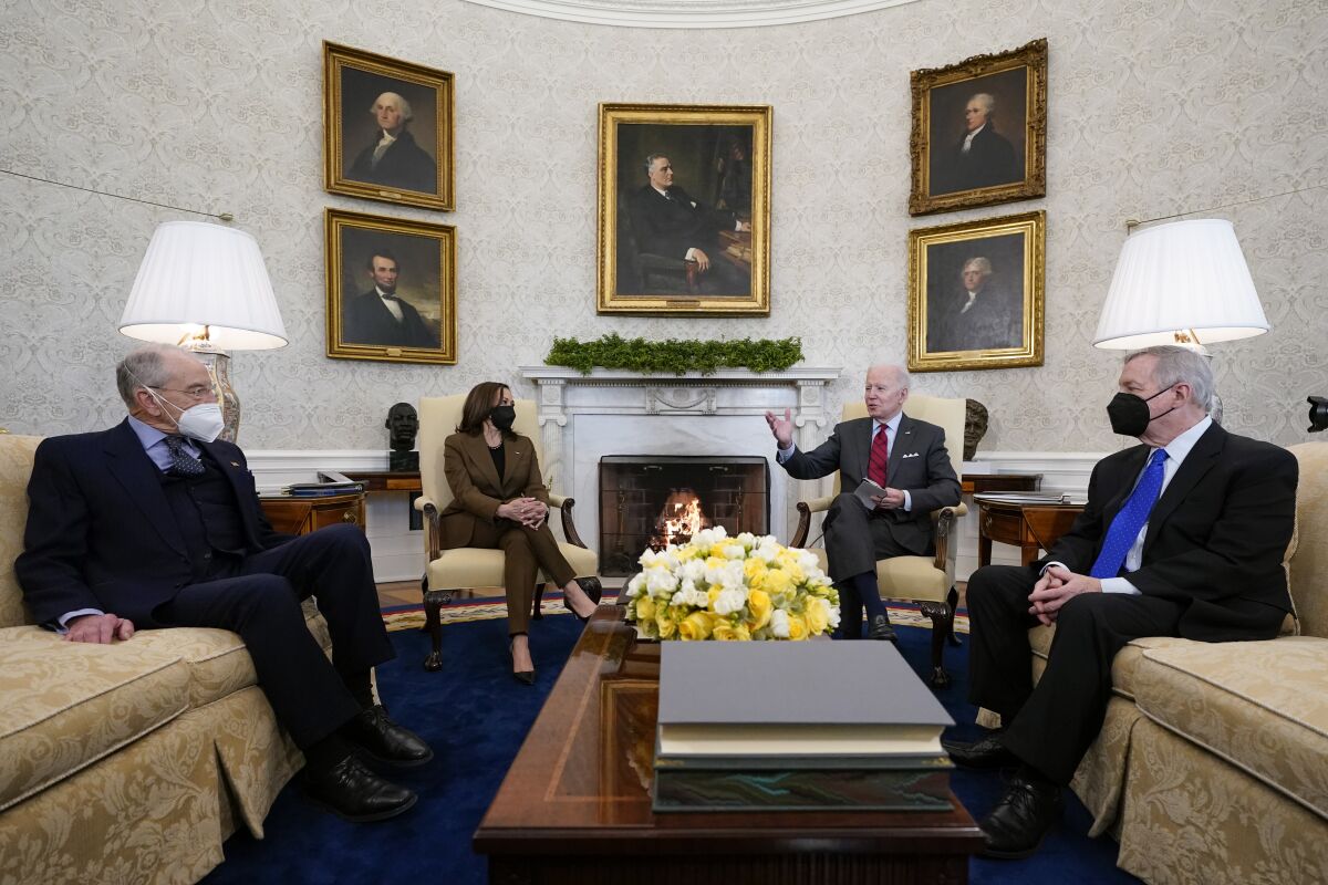 Four people sit in the White House Oval Office.